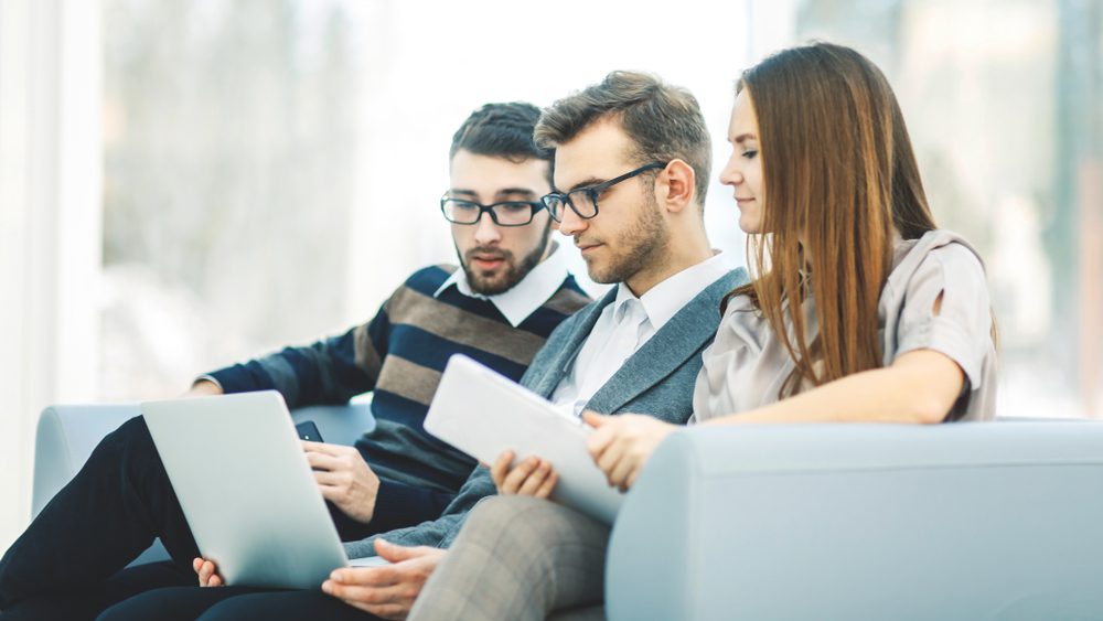 Employees with laptops and tablets sitting in an office